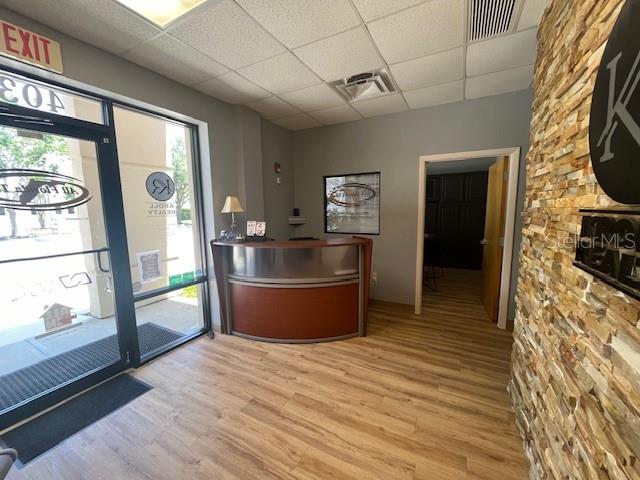 This office reception area features a curved wooden desk, light wood flooring, and stone accents — 4031 W STATE ROAD 46 UNIT C, SANFORD, FL