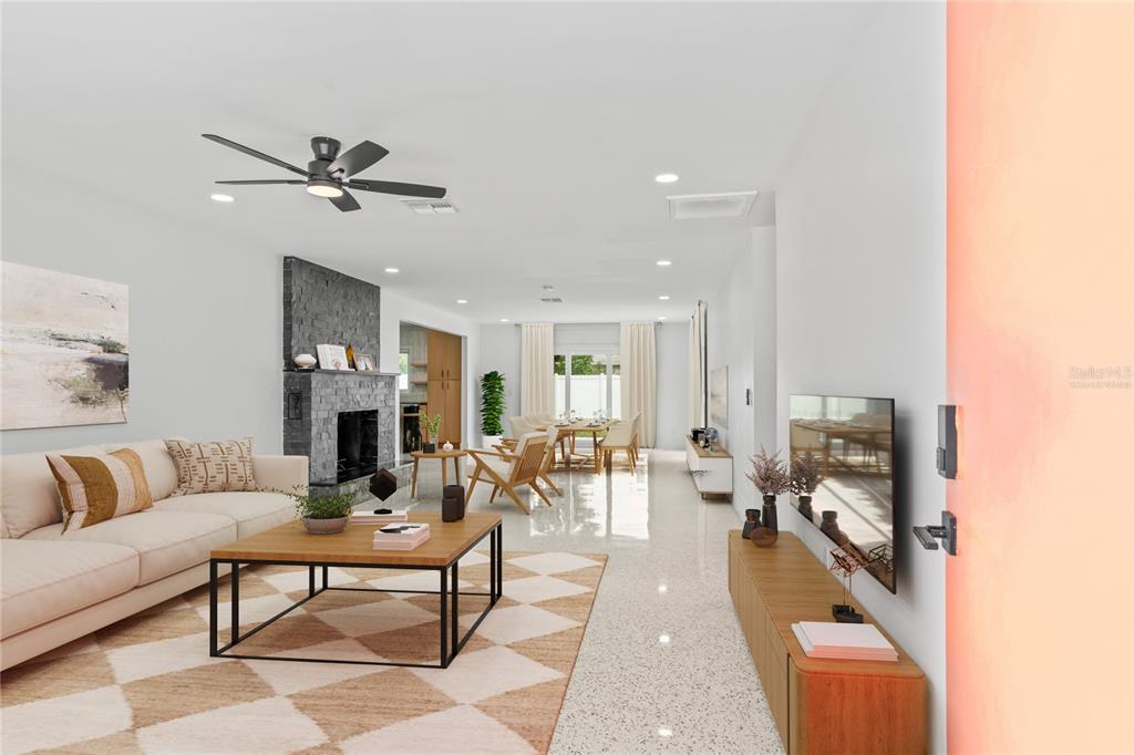 A bright, open-concept living and dining area features a stone fireplace and tile flooring — 123 8TH STREET, BELLEAIR BEACH, FL