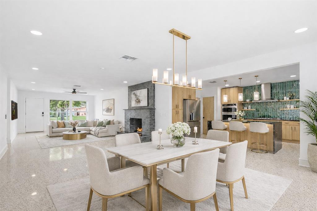 An open-concept living and dining area features a stone fireplace, modern kitchen, and terrazzo flooring — 123 8TH STREET, BELLEAIR BEACH, FL