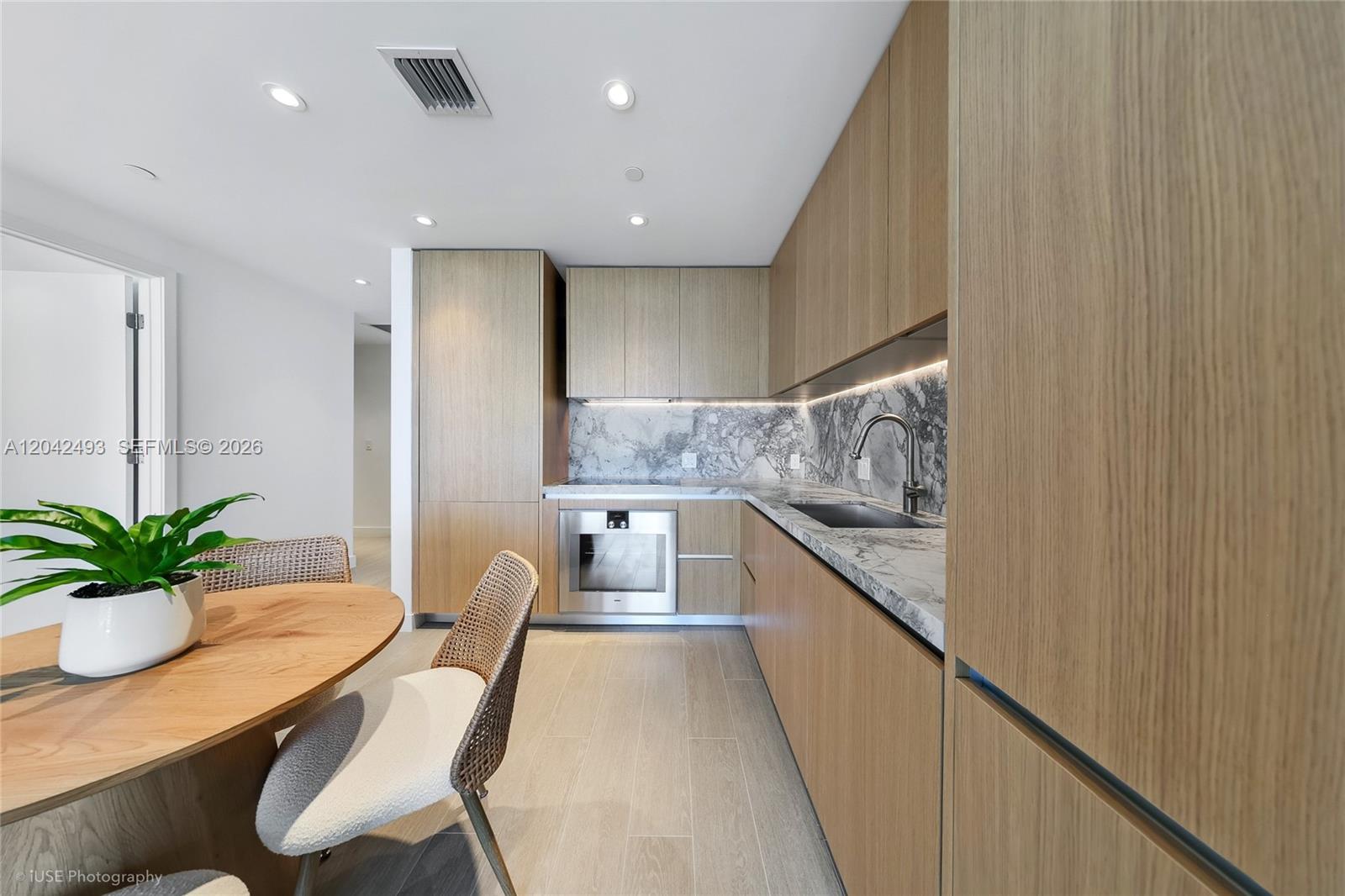 A modern kitchen features light wood cabinetry, marble countertops, and a stainless steel oven — 500 Alton Rd # 1906, Miami Beach FL 33139, MIAMI BEACH, FL