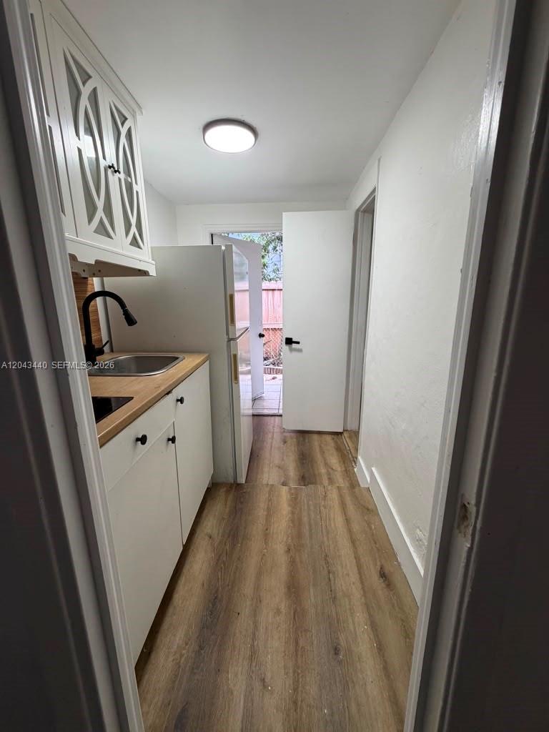 A narrow kitchen features white cabinets, a wood countertop, a sink, and a refrigerator — 2137 NW 1st Ter, Miami FL 33125, MIAMI, FL