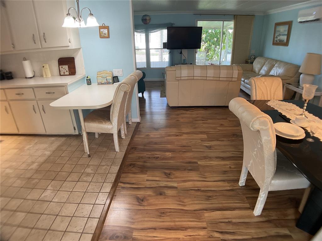 An open-concept living and dining area features wood-look flooring, light blue walls, and white cabinetry — 2100 KINGS HIGHWAY TRAIL UNIT 116, PORT CHARLOTTE, FL