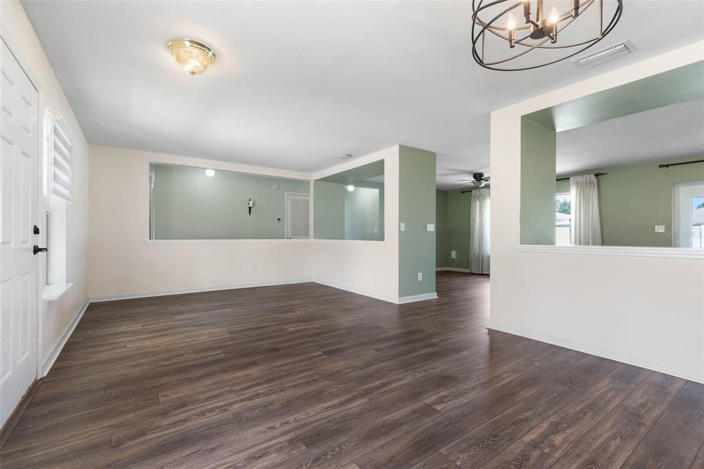 An empty room with wood-look flooring, white walls, and large interior cutouts looking into another space — 27 WOOD ARBOR LANE, PALM COAST, FL