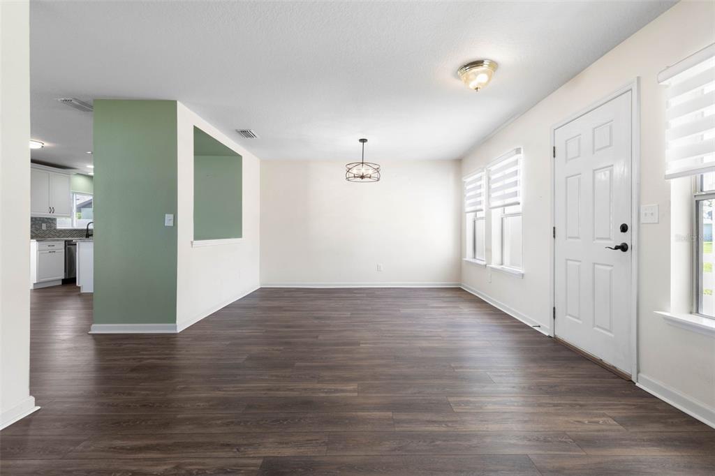 A dining area with dark wood-look flooring, a green accent wall, and a modern chandelier — 27 WOOD ARBOR LANE, PALM COAST, FL