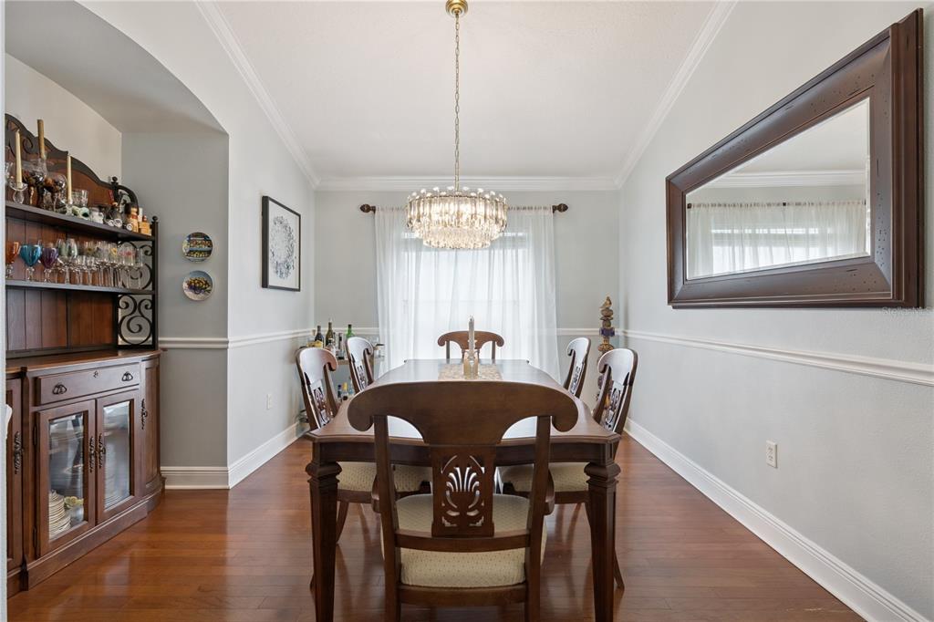 A living room features hardwood floors, a tufted sofa, a chandelier, and double glass doors — 9943 HERON POINTE DRIVE, ORLANDO, FL