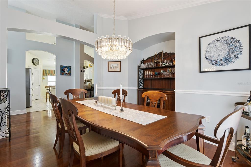 A living room features hardwood floors, a tufted sofa, a chandelier, and a wall-mounted television — 9943 HERON POINTE DRIVE, ORLANDO, FL