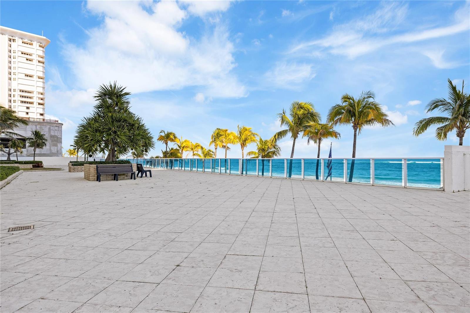 A paved oceanfront terrace features a bench, palm trees, and a glass railing overlooking water — 1360 S Ocean Boulevard # 403, Pompano Beach FL 33062, POMPANO BEACH, FL