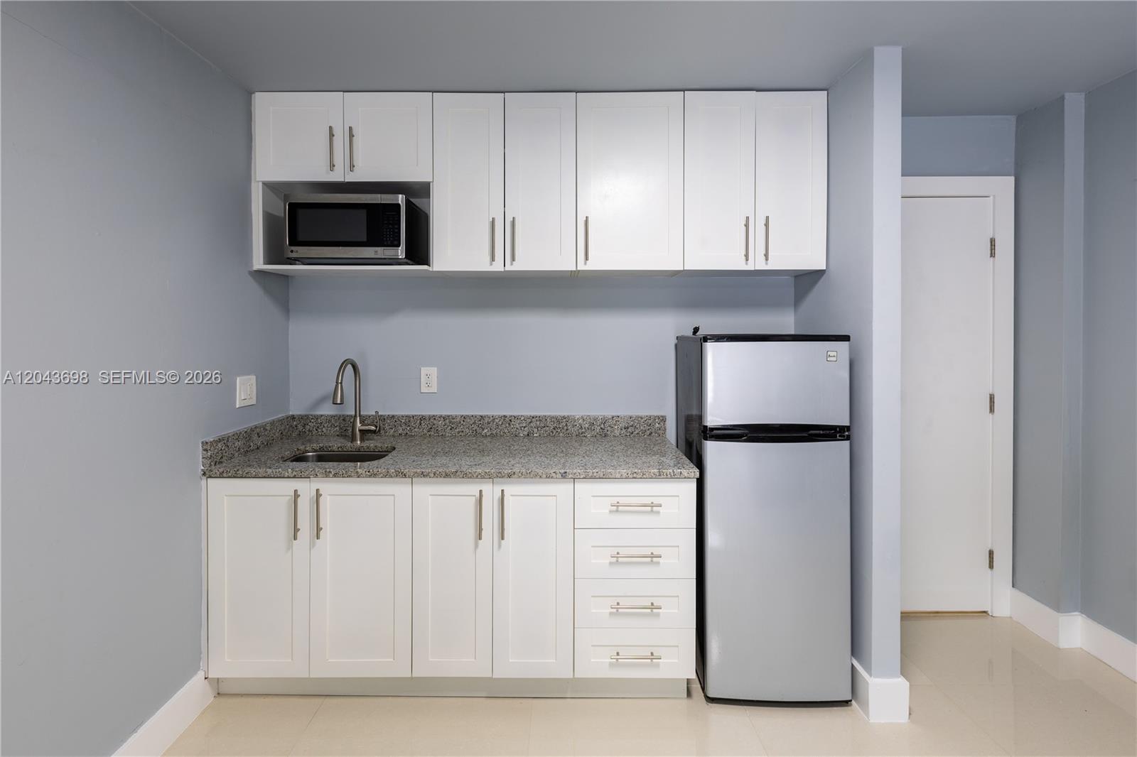 A kitchenette features white cabinets, granite countertops, a stainless steel refrigerator, and a microwave — 4538 SW 1st St # 3, Miami FL 33134, MIAMI, FL