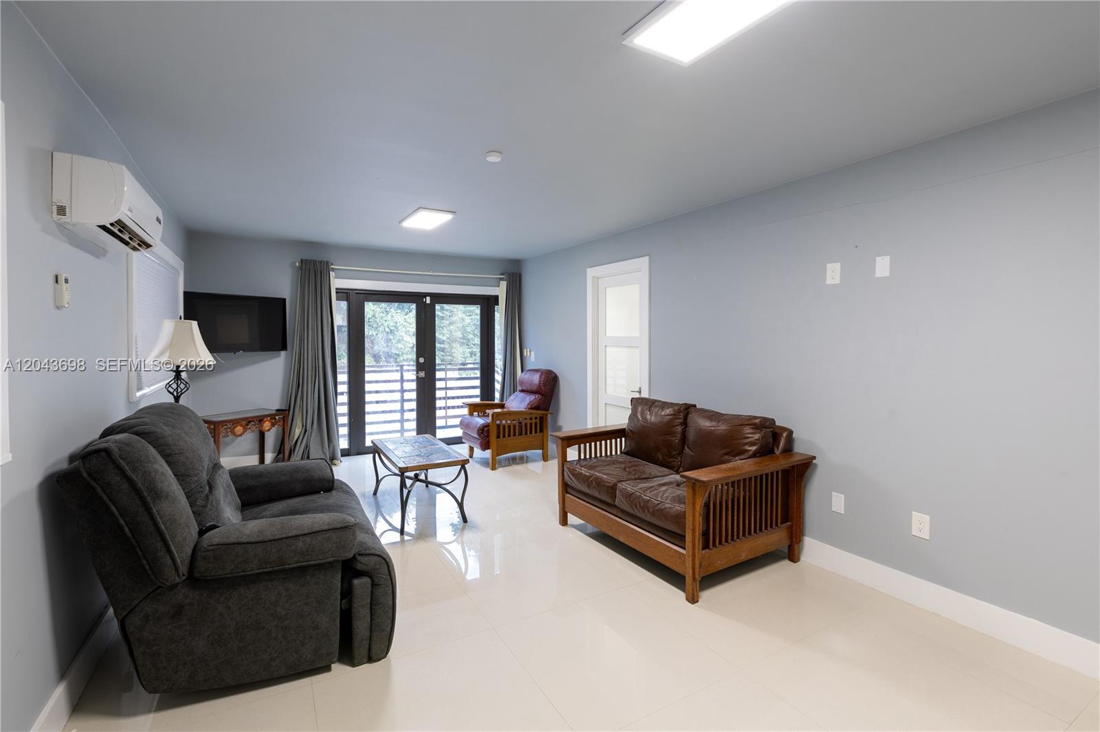 A living room features light blue walls, tile flooring, a brown leather sofa, and a recliner — 4538 SW 1st St # 3, Miami FL 33134, MIAMI, FL