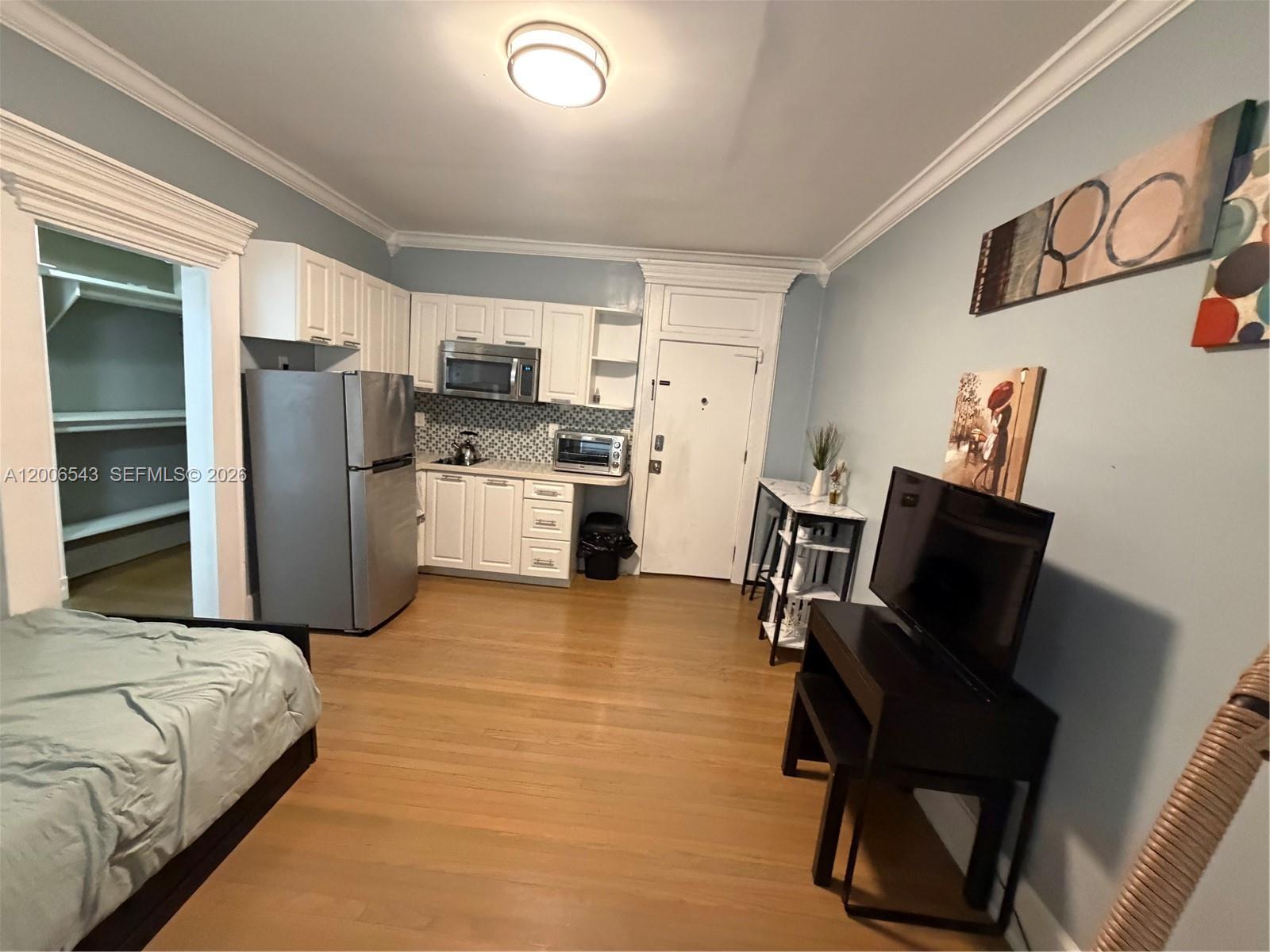 A studio apartment features a kitchen with white cabinets, stainless appliances, and hardwood floors — 124 Mendoza Ave # 2A, Coral Gables FL 33134, CORAL GABLES, FL