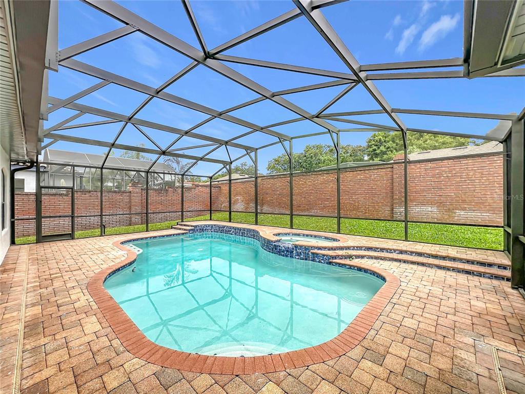 A screened-in swimming pool and spa with a brick patio and surrounding brick wall — 7426 POINTE VENEZIA DRIVE, ORLANDO, FL