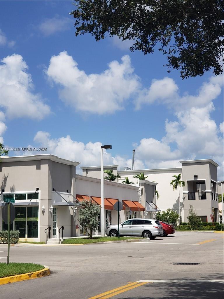A low-angle exterior view of a modern commercial building with orange awnings under a sky — 2101 SW 101st Ave # 203, Miramar FL 33025, MIRAMAR, FL