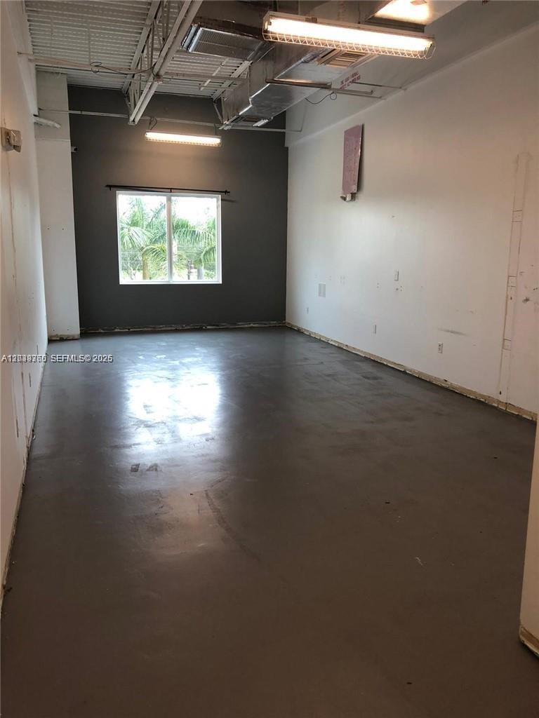 An empty room features gray painted floors, white walls, and an exposed industrial ceiling — 2101 SW 101st Ave # 203, Miramar FL 33025, MIRAMAR, FL