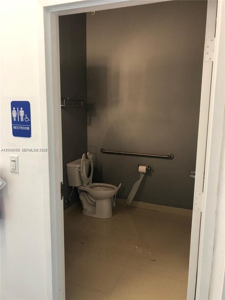 A small, accessible restroom features a toilet, a grab bar, and a wall-mounted sign — 2101 SW 101st Ave # 203, Miramar FL 33025, MIRAMAR, FL