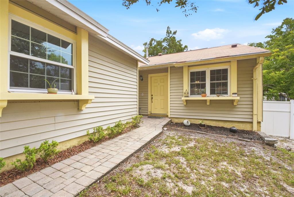 A tan house with yellow trim features a paved walkway leading to the front door — 1356 LANDRY CIRCLE, LONGWOOD, FL