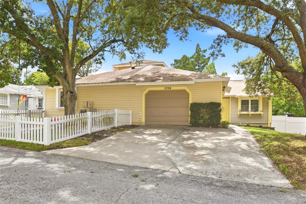 A single-story house with yellow siding, a one-car garage, and a white picket fence — 1356 LANDRY CIRCLE, LONGWOOD, FL