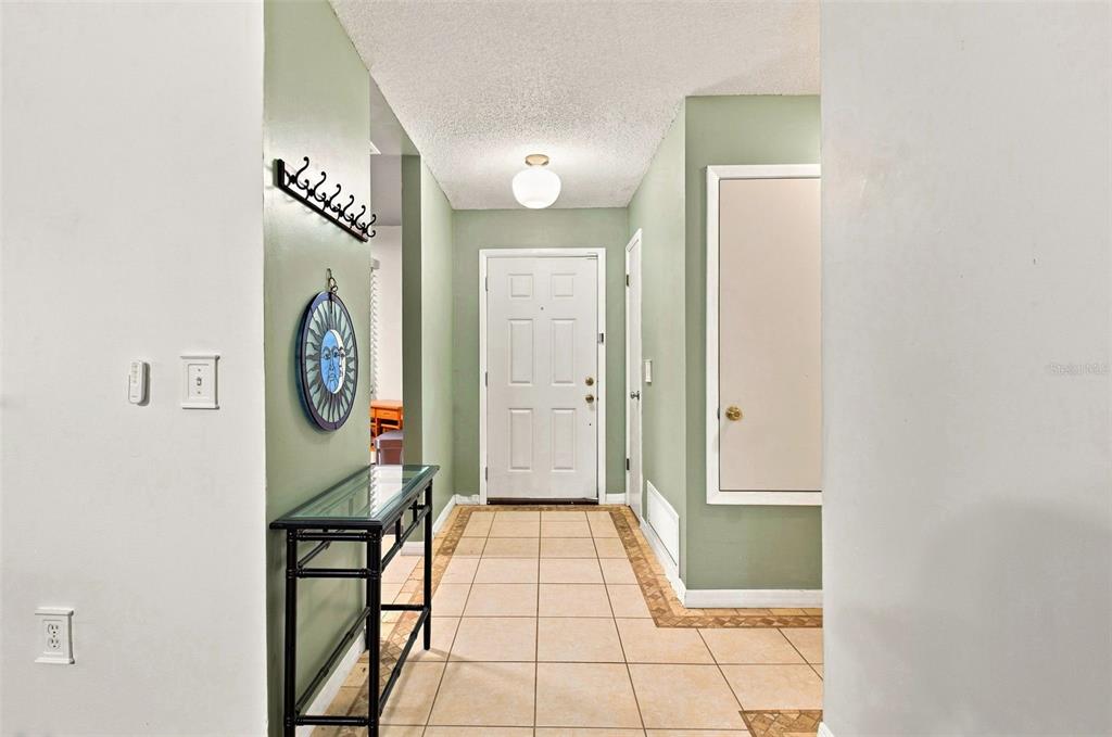 An entryway features a tiled floor, a console table, and a white front door — 1356 LANDRY CIRCLE, LONGWOOD, FL