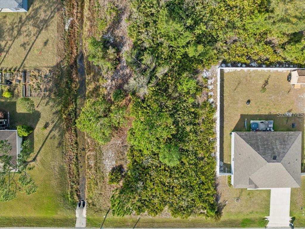 An aerial view shows a vacant, wooded residential lot situated between two developed properties — 10 ROCKING LN, PALM COAST, FL