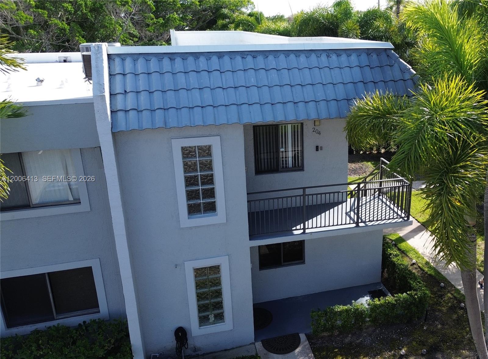 An exterior view of a two-story residential building with a blue tiled mansard roof — 16501 Blatt Blvd # 204, Weston FL 33326, WESTON, FL