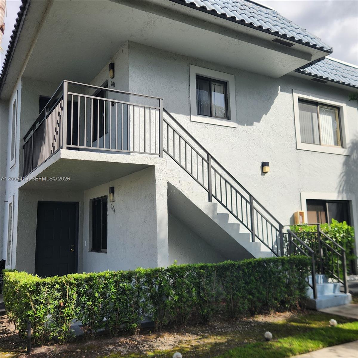 A two-story building exterior features a balcony, an outdoor staircase, and a manicured hedge — 16501 Blatt Blvd # 204, Weston FL 33326, WESTON, FL