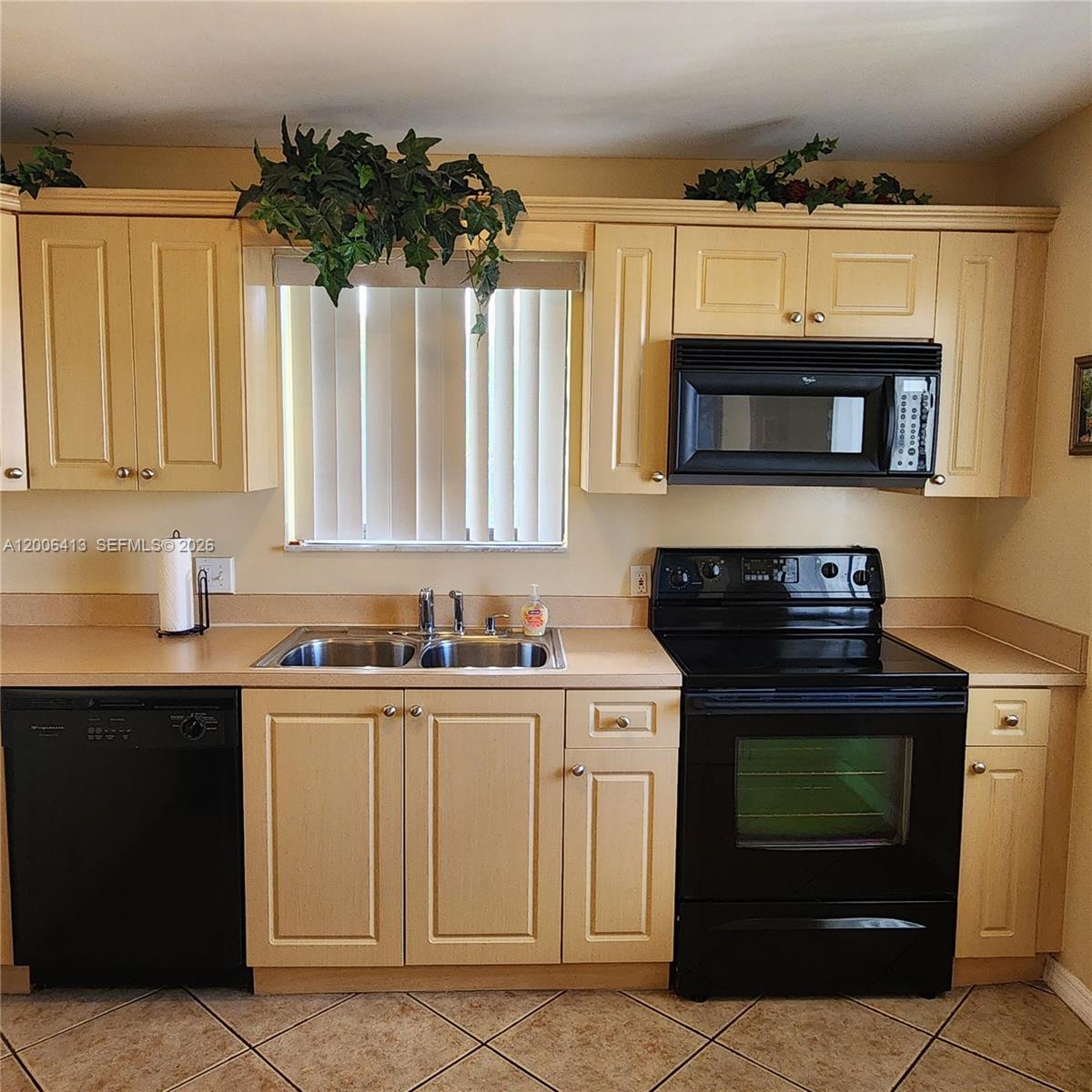 A kitchen features light-colored wood cabinets, black appliances, a double sink, and tile flooring — 16501 Blatt Blvd # 204, Weston FL 33326, WESTON, FL