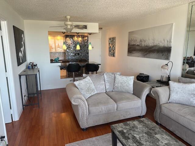 A living room with wood floors, a grey sofa, and a kitchen bar area — 531 N Ocean Boulevard # 903, Pompano Beach FL 33062, POMPANO BEACH, FL