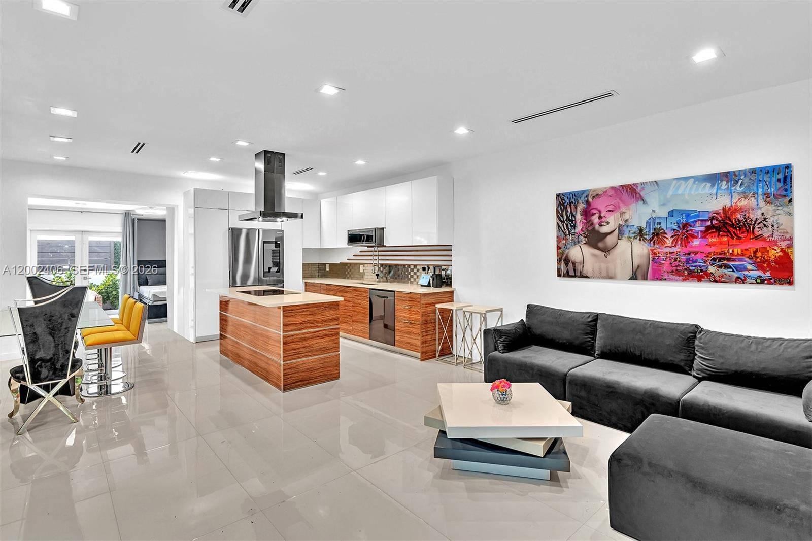 A modern open-concept kitchen and living area features white cabinetry, wood-toned islands, and tile flooring — 1002 10th St # 1002, Miami Beach FL 33139, MIAMI BEACH, FL