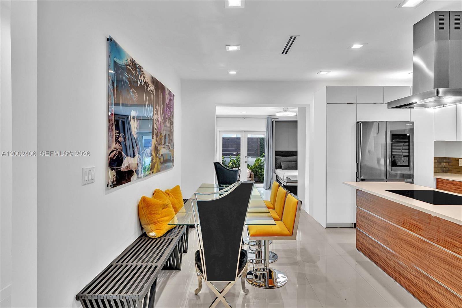A dining area features a glass table, yellow chairs, a bench, and wall art — 1002 10th St # 1002, Miami Beach FL 33139, MIAMI BEACH, FL