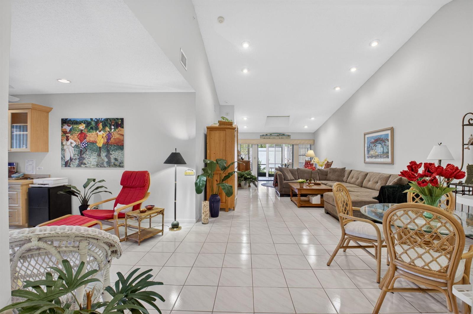 An open-concept living and dining area features white tile floors and a vaulted ceiling — 10039 Andrea Lane # A, Boynton Beach FL 33437, BOYNTON BEACH, FL
