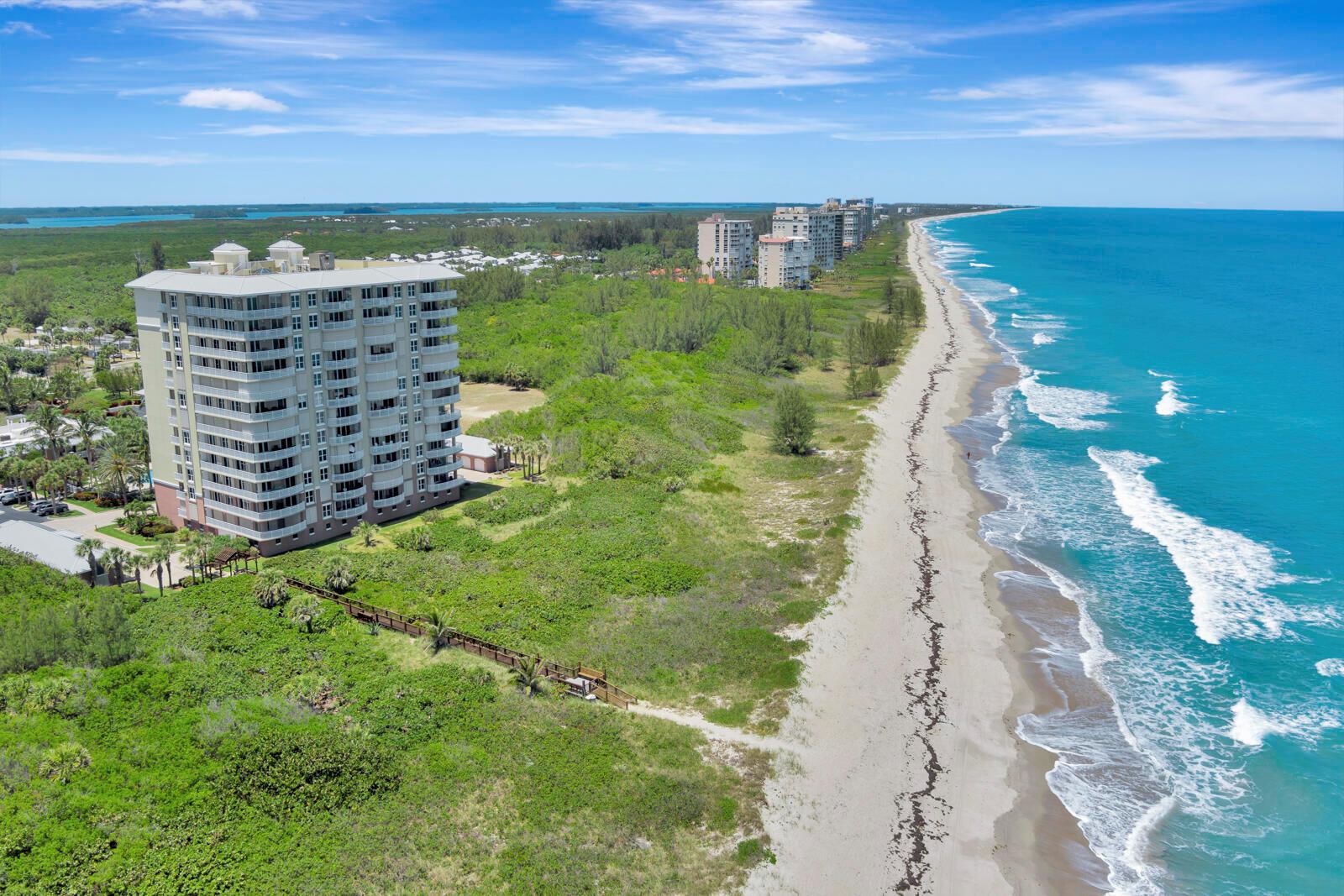 An aerial view shows a tall residential building situated next to a sandy beach — FORT PIERCE, FL