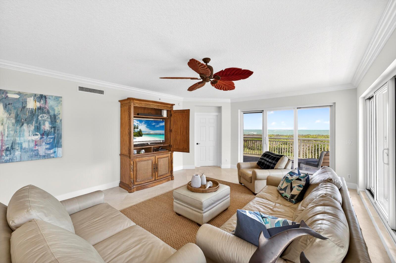 A living room with leather sofas, a wooden entertainment center, and a view of the ocean — FORT PIERCE, FL
