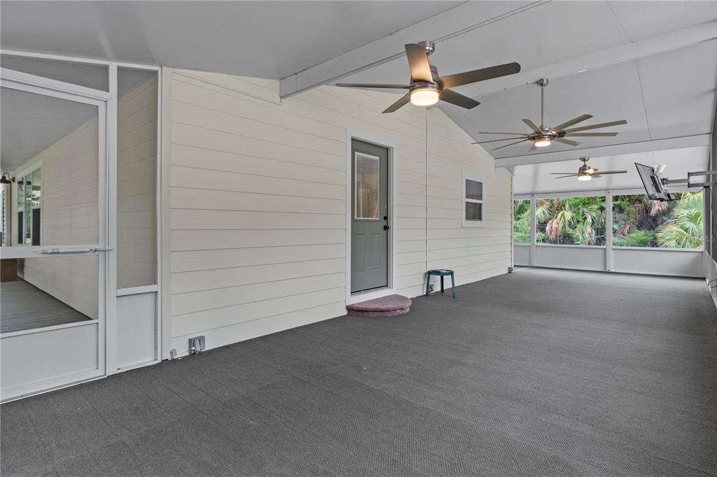 A spacious screened-in porch features light-colored horizontal siding, three ceiling fans, and gray carpeting — 11720 W NORTH PLACE, HOMOSASSA, FL