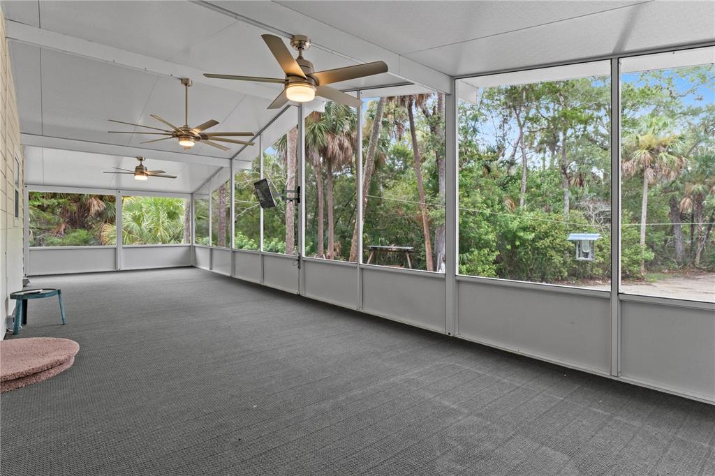 A large screened-in porch features gray carpeting, three ceiling fans, and views of trees — 11720 W NORTH PLACE, HOMOSASSA, FL