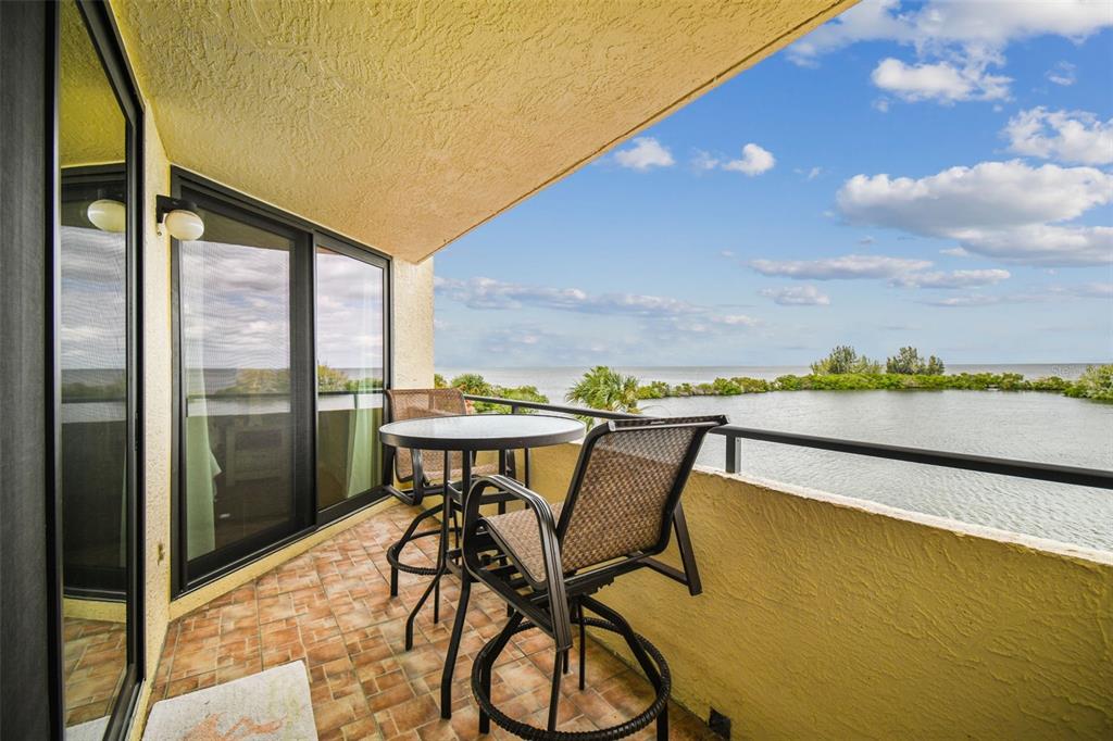 A balcony with a small table and two chairs overlooks a body of water — 5915 SEA RANCH DRIVE UNIT 308, HUDSON, FL