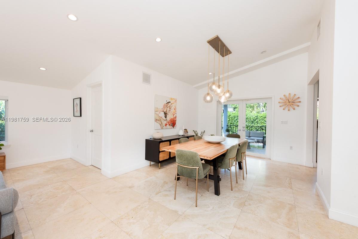 A dining room features a wooden table, green chairs, and a modern light fixture — 717 Benevento Ave, Coral Gables FL 33146, CORAL GABLES, FL