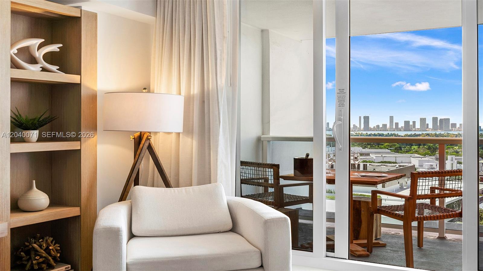 A living room with a white armchair and floor lamp opens onto a balcony view — 102 24 # 1545, Miami Beach FL 33139, MIAMI BEACH, FL