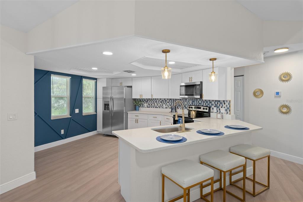 A kitchen with white cabinets, a quartz island, and a blue accent wall with trim — 8643 WOODBRIDGE DR, NEW PORT RICHEY, FL