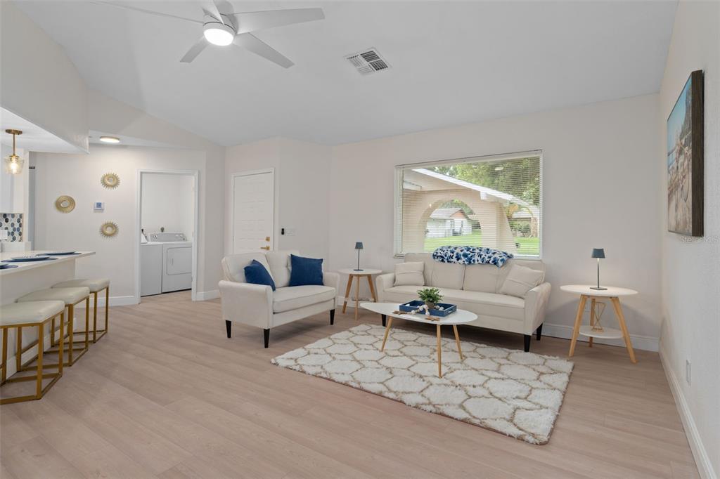 A living room features light wood floors, a white sofa, an armchair, and a rug — 8643 WOODBRIDGE DR, NEW PORT RICHEY, FL