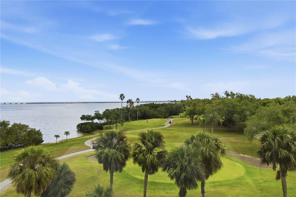 An elevated view of a golf course green beside a bay with a distant bridge — 2616 COVE CAY DRIVE UNIT 502, CLEARWATER, FL