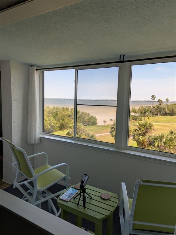 A sunroom features two lime green chairs, a small table, and a view of water — 2616 COVE CAY DRIVE UNIT 502, CLEARWATER, FL