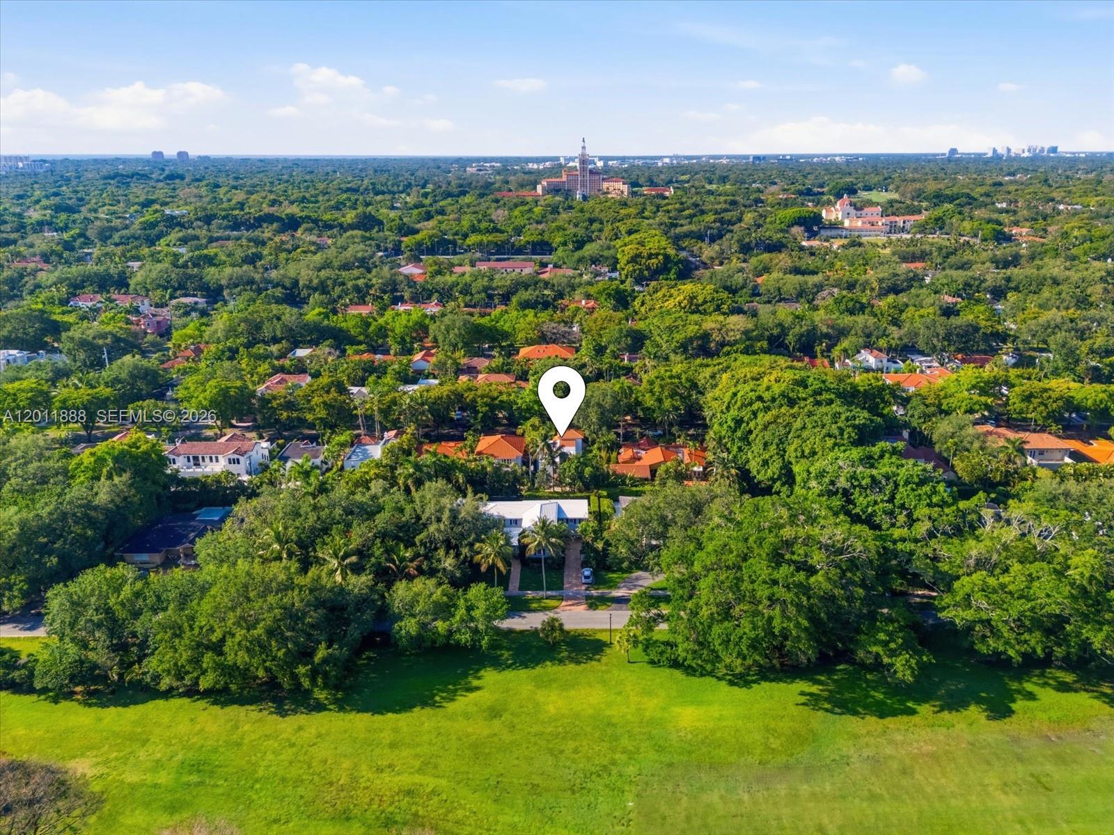 An aerial view shows a house with a white roof nestled among dense trees — 1137 Asturia Ave, Coral Gables FL 33134, CORAL GABLES, FL