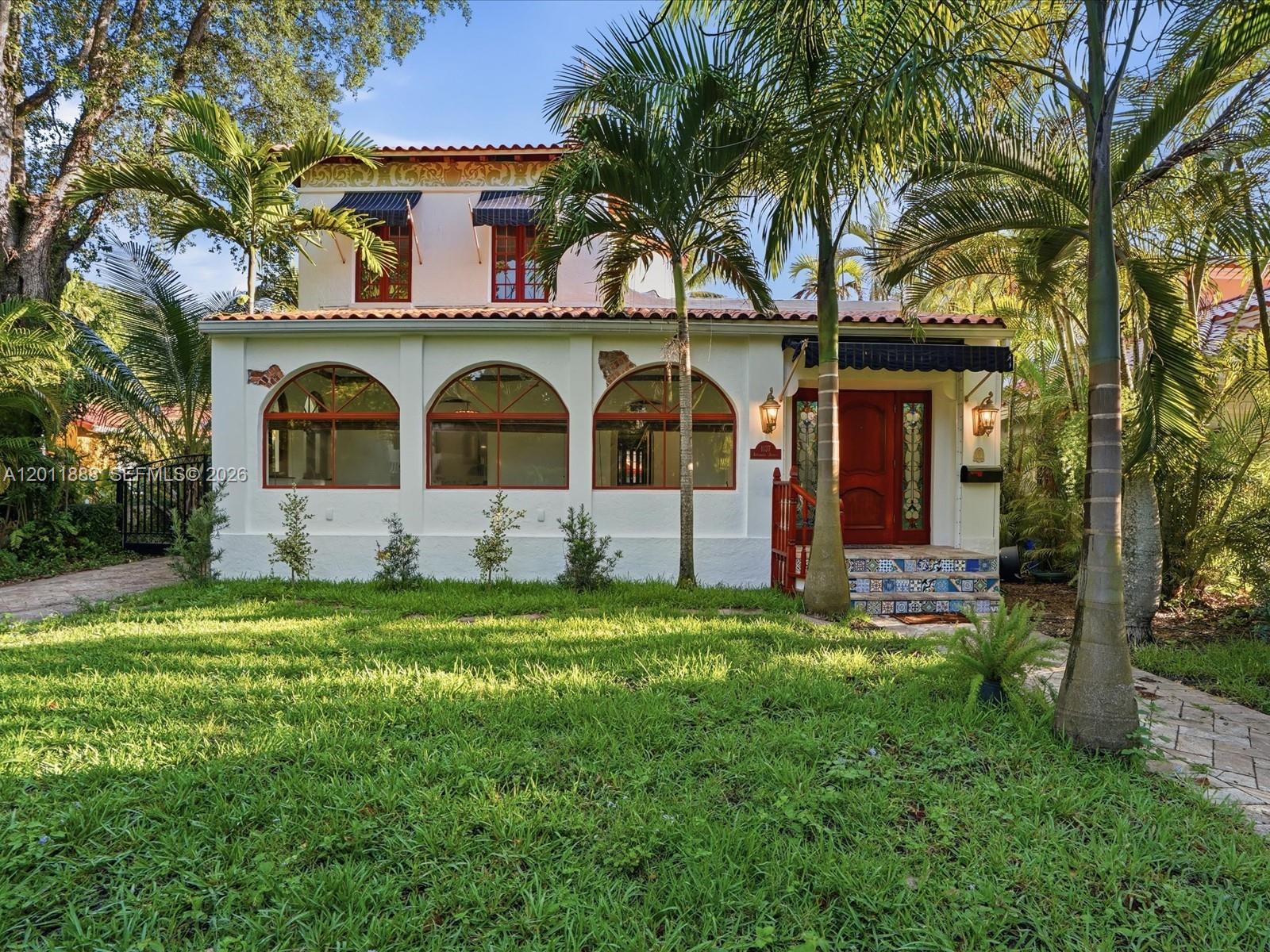 A two-story Mediterranean-style house with arched windows, a tiled roof, and palm trees in front — 1137 Asturia Ave, Coral Gables FL 33134, CORAL GABLES, FL