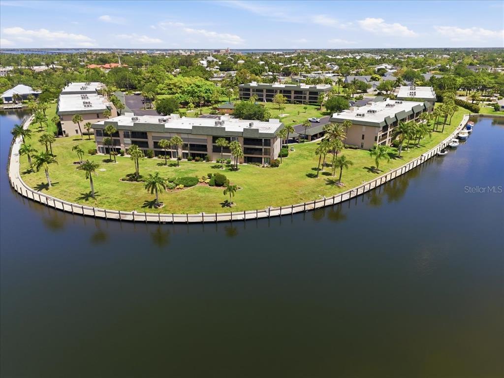 An aerial view shows multi-story apartment buildings situated on a grassy peninsula surrounded by water — 601 SHREVE STREET UNIT 32B, PUNTA GORDA, FL