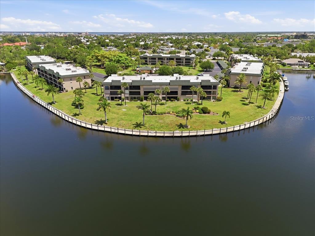 An aerial view shows three multi-story apartment buildings situated on a grassy waterfront peninsula — 601 SHREVE STREET UNIT 32B, PUNTA GORDA, FL
