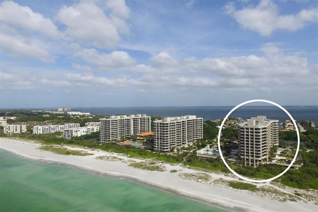 An aerial view of a beach with several high-rise apartment buildings, one circled in white — 1211 GULF OF MEXICO DRIVE UNIT 405, LONGBOAT KEY, FL