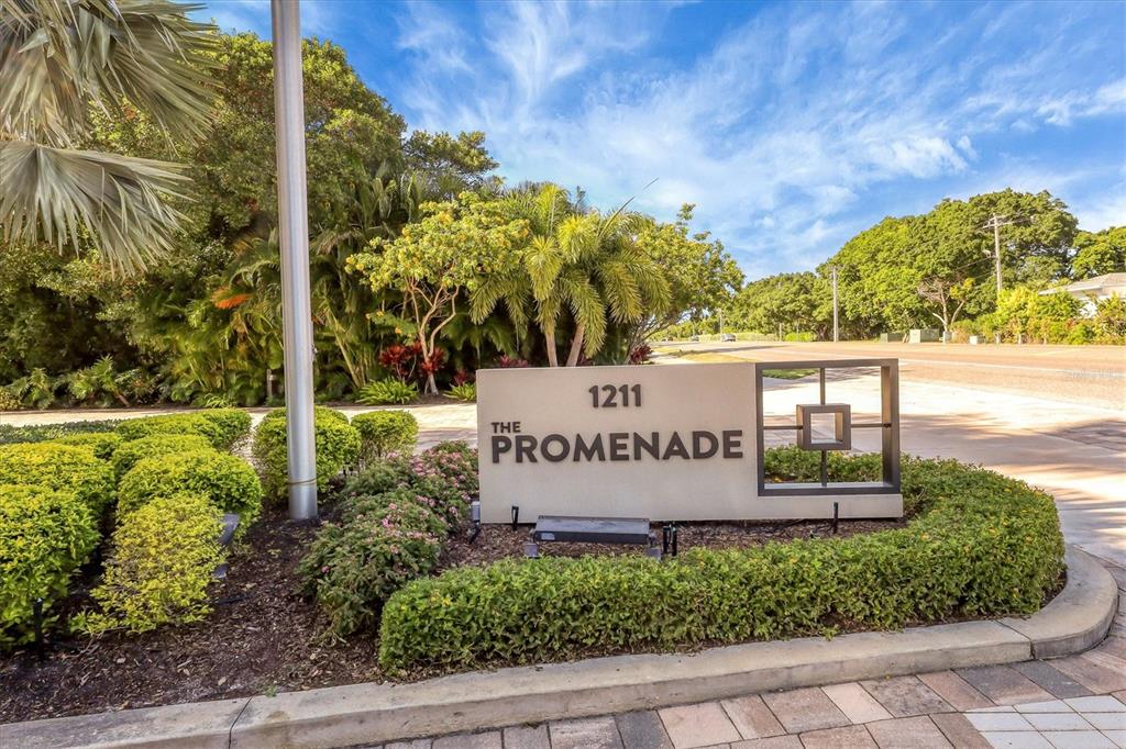 A beige monument sign for The Promenade stands in a landscaped garden bed — 1211 GULF OF MEXICO DRIVE UNIT 405, LONGBOAT KEY, FL