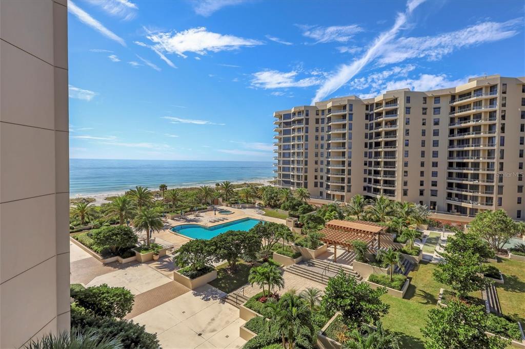 An elevated view of a swimming pool, landscaped grounds, and a beachside high-rise apartment building — 1211 GULF OF MEXICO DRIVE UNIT 405, LONGBOAT KEY, FL