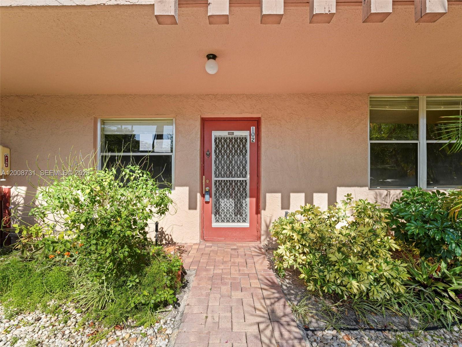 A red front door with a security screen leads to a unit numbered 102 — 480 NW 76th Ave # 102, Margate FL 33063, MARGATE, FL