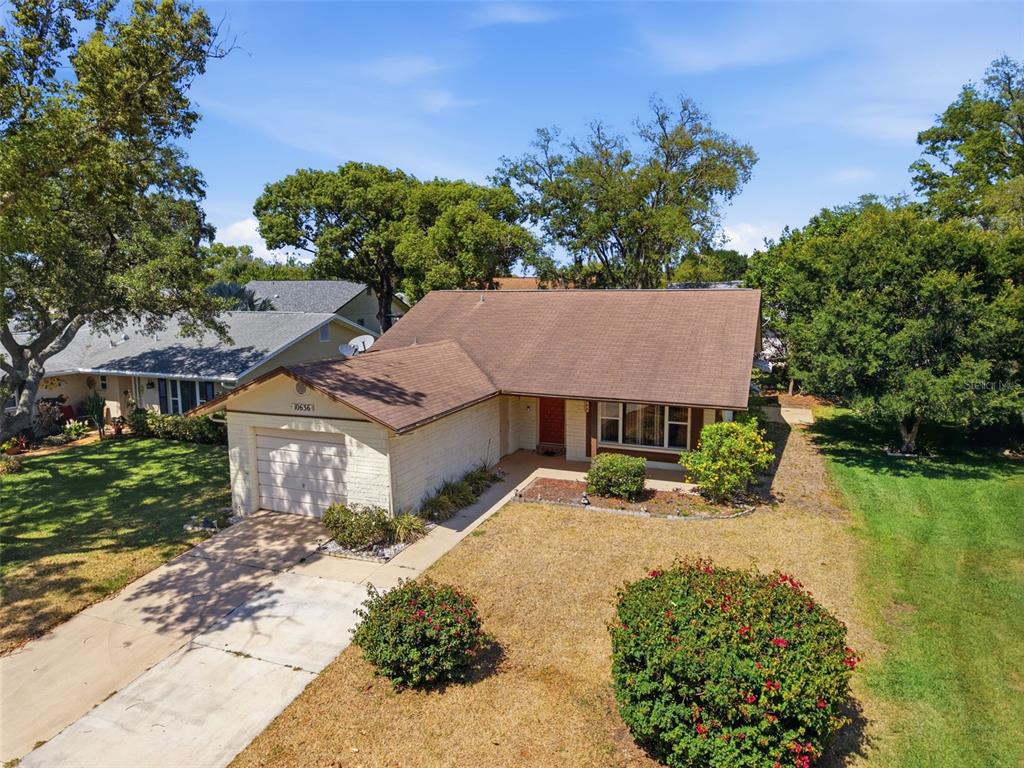 An aerial view of a single-story house with a brown roof and a concrete driveway — 10636 SALAMANCA DRIVE, PORT RICHEY, FL