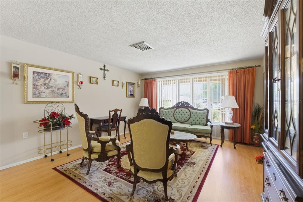 A living room features traditional furniture, a patterned area rug, and orange curtains — 10636 SALAMANCA DRIVE, PORT RICHEY, FL